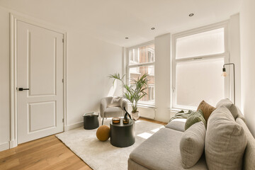 a living room with white walls and hardwood flooring, there is a plant in the corner of the room