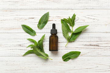 Natural Mint Essential Oil in a Glass Bottle. organic cosmetics with herbal extracts of mint on colored background - obrazy, fototapety, plakaty