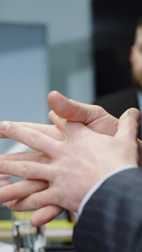 Vertical screen: Businessman gesturing with hands during meeting in office, blurred coworkers on background discussing project, sharing ideas, closeup shot. Concept of leadership