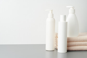 Obraz na płótnie Canvas Set of blank cosmetic bottles and towels on gray background