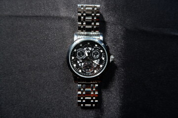 Stainless watch with black background.