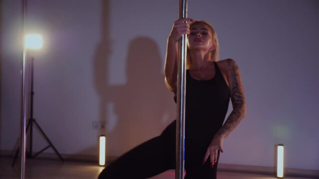 A beautiful woman dances an exotic pole dance. Erotic dance on a pole.	