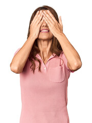 Middle-aged woman portrait in studio setting afraid covering eyes with hands.