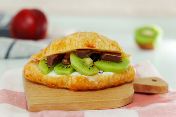 Croissant stuffed with curd cheese, with kiwi ricotta and chocolate. Homemade croissants.
