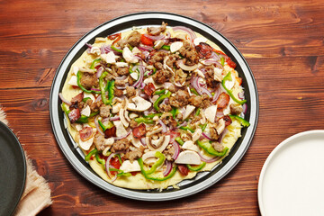 Raw St. Louis-Style Pizza homemade on a wooden background, with cheese, pepper, bacon onion