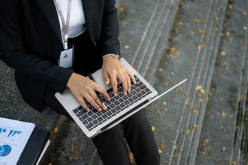 Top view image of a busy businesswoman is working on her laptop while sitting on the stairs.