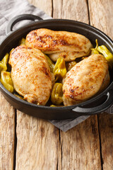 Baked chicken fillet with pepperoncini pepper close-up in a frying pan on the table. Vertical