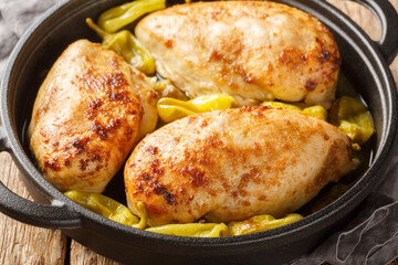 Home-baked chicken fillet with peperoncini peppers in a spicy sauce close-up in a frying pan on the...