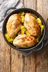 Baked chicken fillet with pepperoncini pepper close-up in a frying pan on the table. Vertical top view from above
