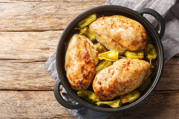 Home-baked chicken fillet with peperoncini peppers in a spicy sauce close-up in a frying pan on the table. Horizontal top view from above