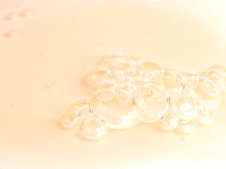 macro of orange liquid face cleansing gel or soap with bubbles. Close up of skin care product