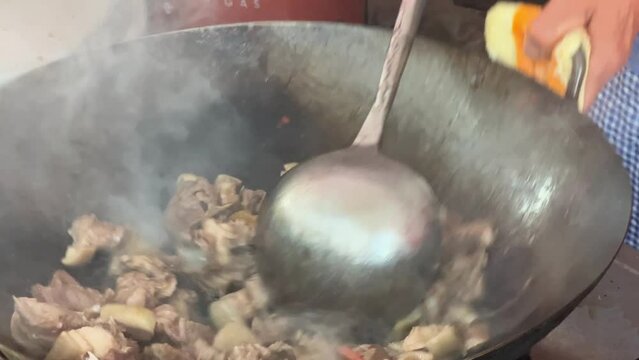 A chef is stir-frying mutton in a wok