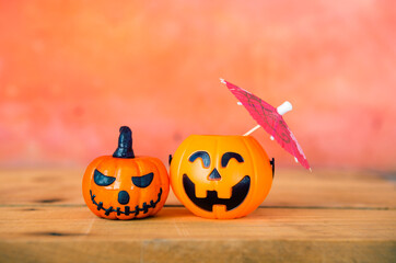 Two Halloween pumpkin with paper umbrella with space on orange cement wall, Happy halloween card background idea