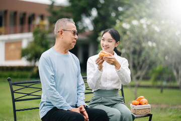 Elderly asian senior man on lchair with Asian careful caregiver. Nursing home hospital garden concept..