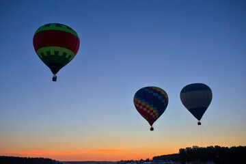 Three Amazing Colorful Air Balloons Levitating Over the Ground Outdoors Against Clear Blue Skies