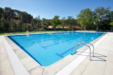 Outdoor swimming pool surrounded by trees. Recreation area. Copy space