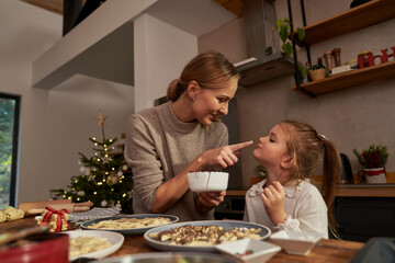 Mother and daughter having fun while decorating gingerbread cookies