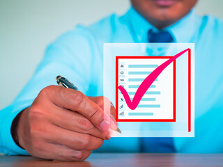 Businessman holding a clipboard with checklist and pen in the office.