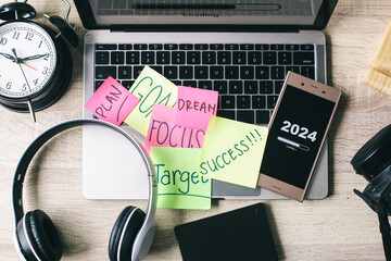 Office desk with 2024 loading bar on smartphone screen. Happy New Year concept.