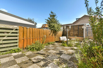 a backyard area with a wooden fence and green plants in the foreground, on a clear blue sky day