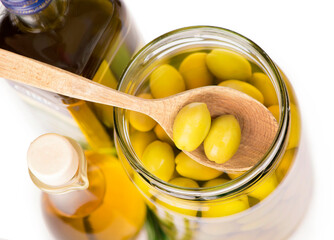 Olive oil and olive branch on table