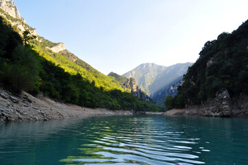 The turquoise blue Lake Lac de Sainte-Croix in the south of France in the Provence region. A lake in the mountains between rocks and cliffs.