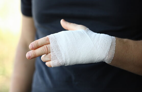 Male hand with tight elastic bandage on arm closeup. Self help sprain concept