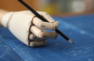 Close-up of prosthesis hand making changes on blueprint. Drawings and circles illustrated on working paper. Business motivation and disabilities concept