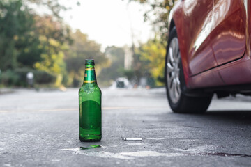 An empty bottle of beer and a half-smoked cigarette thrown on the road.Drunk driver drives...