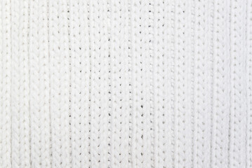 White knitted background. Texture of knitted woolen fabric with vertical lines. Scarf or sweater close-up.