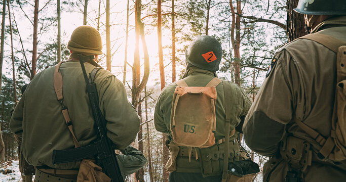 Back View On Re-enactors Dressed As American Infantry Soldier Watch For Bright Sun At Winter Day. Group Of Usa Soldiers Armed Of Sturmgewehr 44 Or Assault Rifle 44. Usa Army Soldiers Of World War Ii.