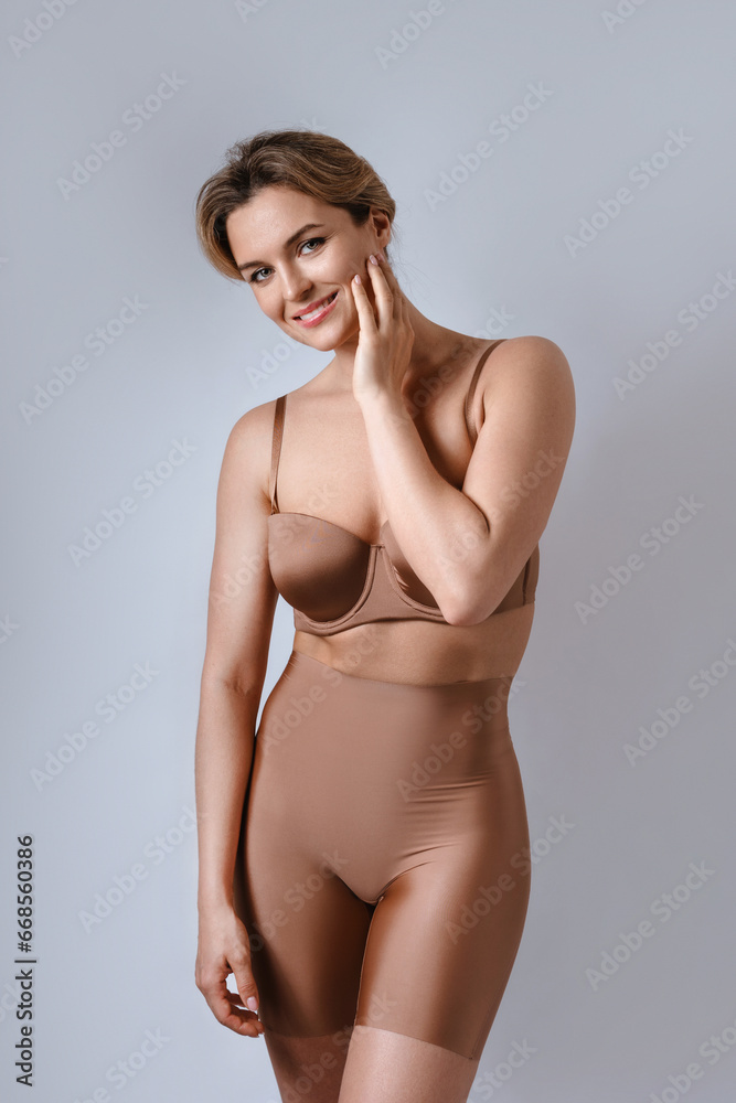 Poster portrait of young attractive woman wearing brown lingerie with high waist shaping briefs against gra