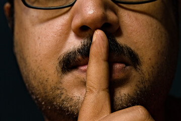 photo of an Asian adult male closing his lips with a finger