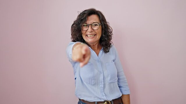Middle age hispanic woman smiling confident pointing with finger to the camera over isolated pink background