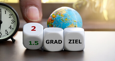 Hand turns dice and changes the expression '1.5 grad ziel' (1.5 degree target) to '2 grad ziel'...