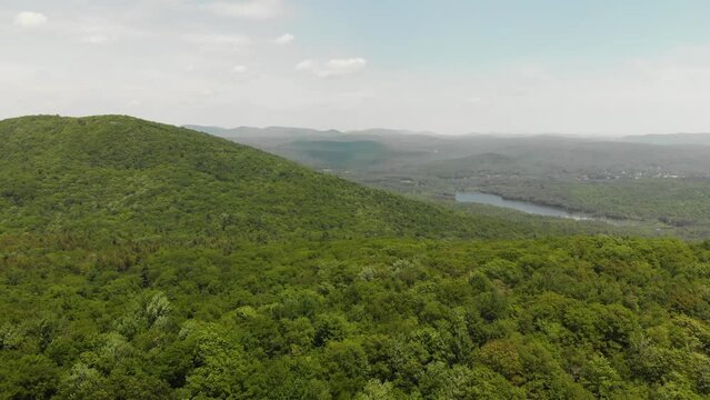 Slow aerial flyover above vast green forest in Upstate New York Adirondack Mountains.