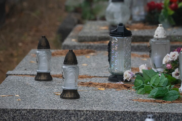 Warsaw, Poland - October 24, 2023: Graves in the cemetery on a cloudy, foggy day. Weather for All Saints' Day. Candles and flowers on graves. - obrazy, fototapety, plakaty
