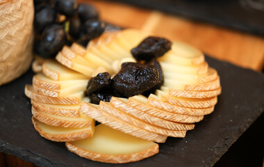 Cheese platter. Deliciour appetizer made of several types of cheese prepared to be served for an event. Appetizer catering food service. Comte, brie, cheddar, camembert cheese along with fruits.