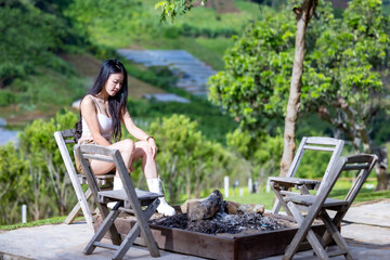 Young asian woman sitting near campfire and admiring nature.Woman traveler relaxing admiring...