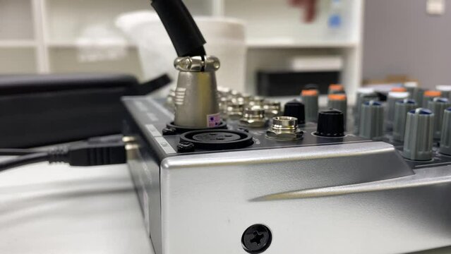 Male technician hand pull microphone plug from audio equipment mixer console controller tool close up view inside studio