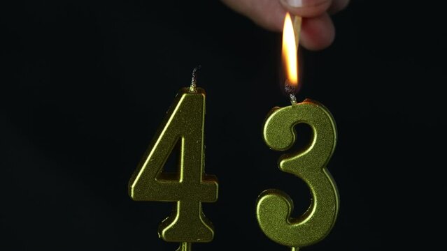 close up on the gold number forty-third candle on a dark background.
