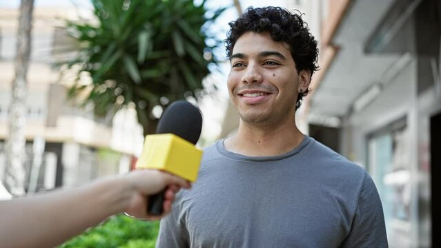 Young latin man having interview smiling at street