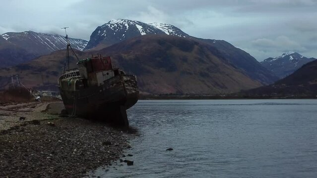 Aerial drone video in 4K of The Old Boat of Corpach (Old Boat of Caol) in Fort William with a snow-topped Nevis in the background
