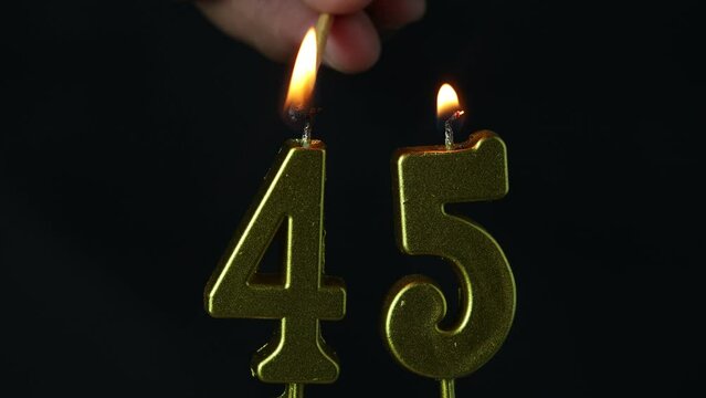 close up on the gold number forty-fifth candle on a dark background.
