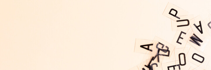 Banner with transparent plastic cards with letters on a beige background. Copy space.