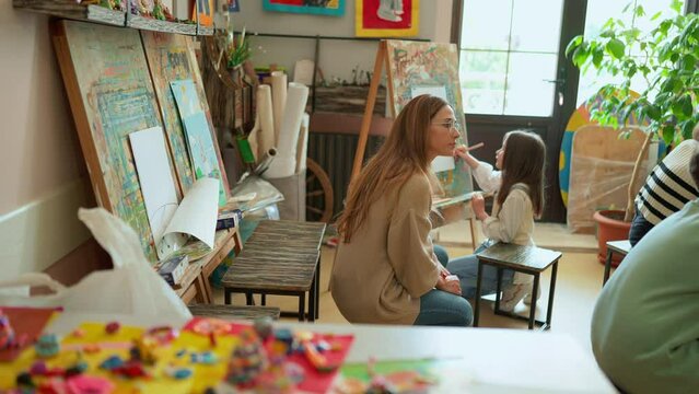 Pensive teacher watches children painting at art school