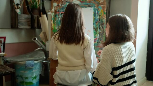 Back view of young girls painting during an illustration class at art school