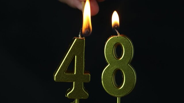 close up on the gold number forty-eighth candle on a dark background.
