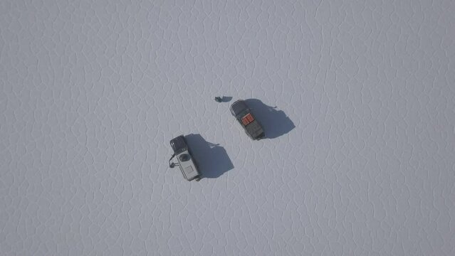 Aerial drone shot of a 4x4 offroad vehicle driving on the Salar de Uyuni salt lake around the isla pescado, fish island, on the biggest salt flat in the world in high altitude of the Andes in the Boli