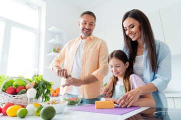 Photo of good mood adorable wife husband little girl preparing tasty salad together indoors apartment kitchen